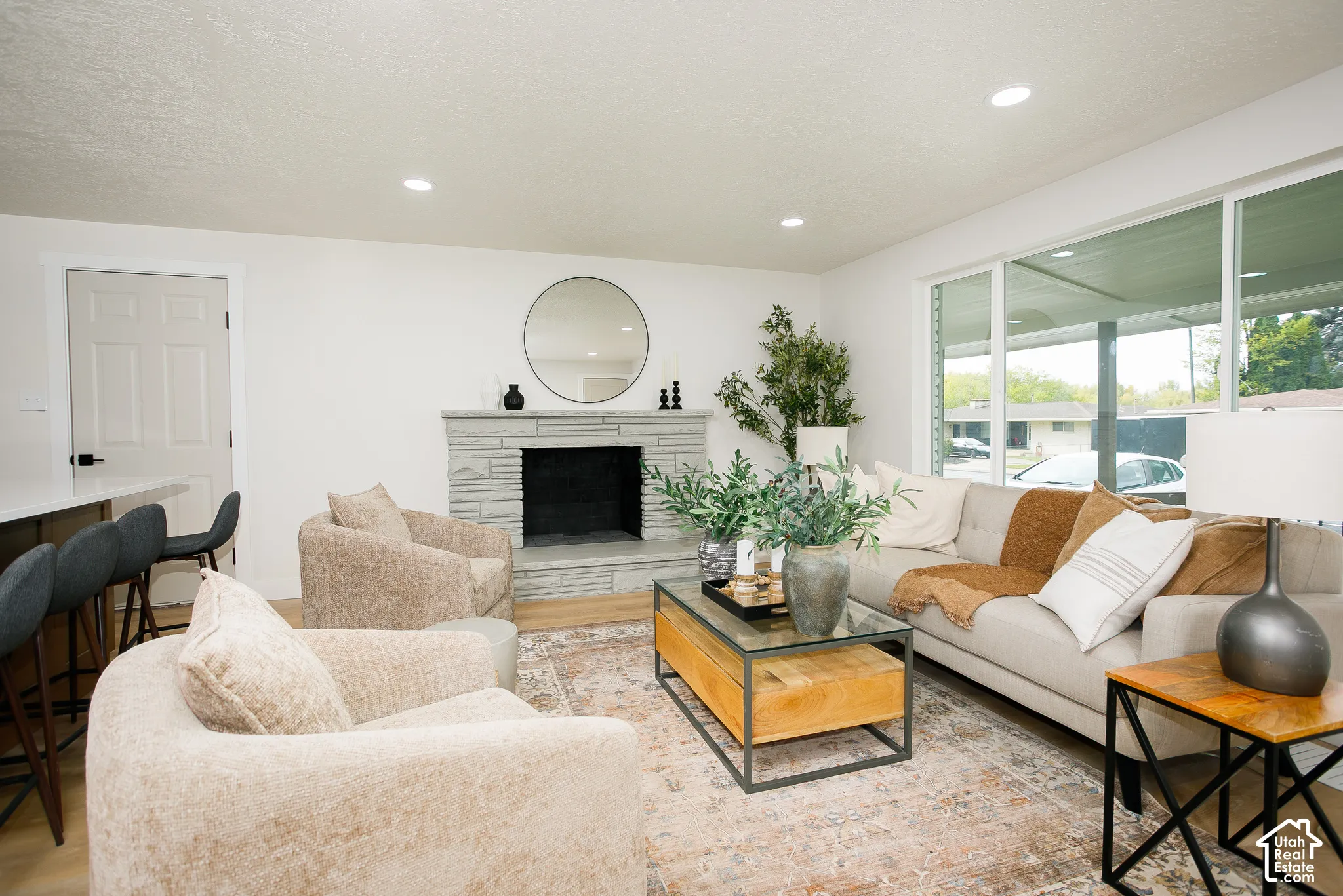 Stone masonry fireplace with a raised hearth, wood-finish flooring, recessed lighting, and large windows