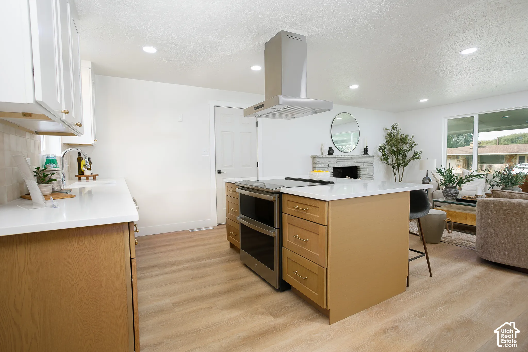 Kitchen featuring wood-finish cabinetry, white countertops, stainless steel appliances, a stainless steel range hood, and wood-finish flooring