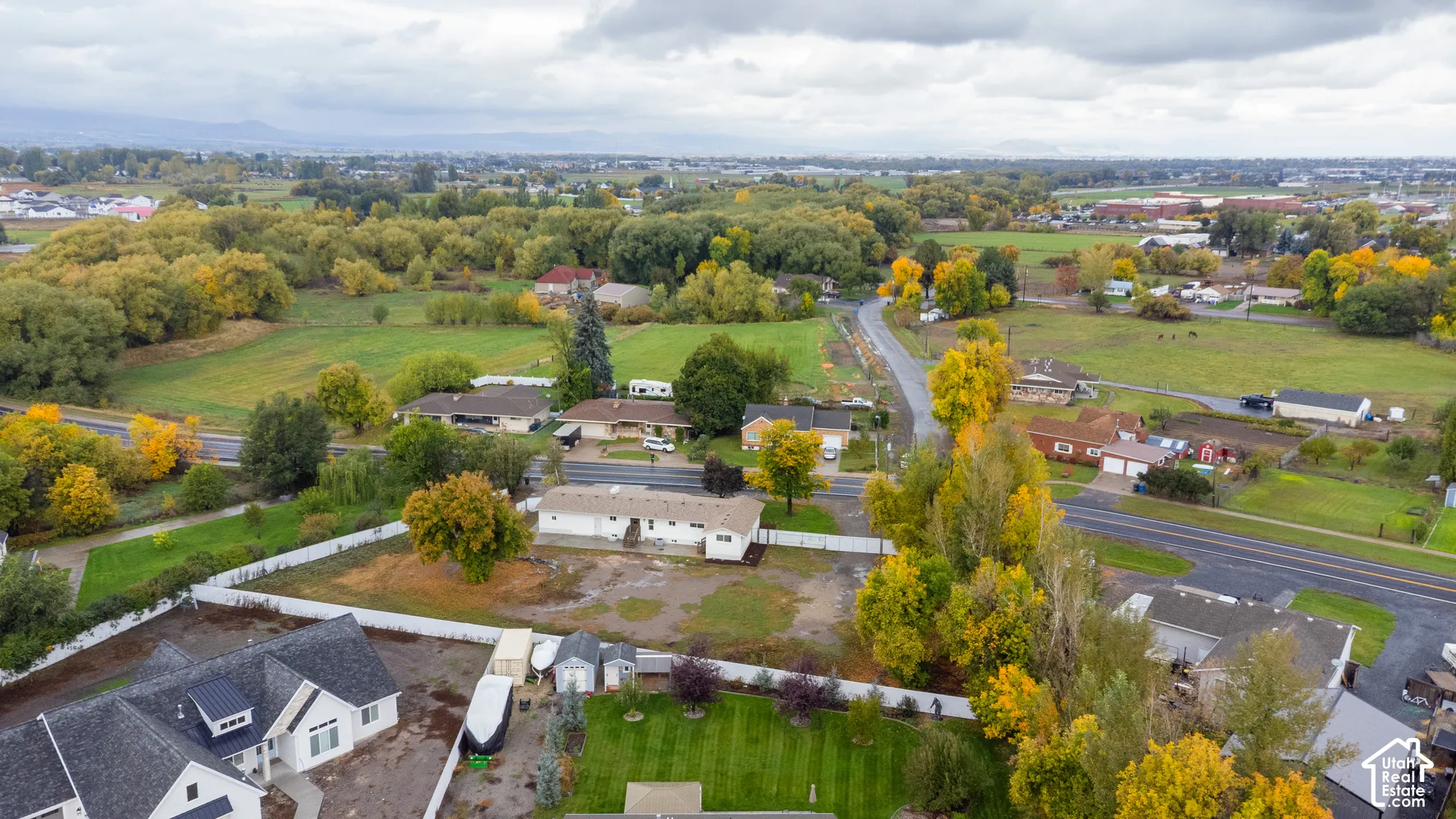 Aerial perspective featuring a multi-acre parcel, residential structure, and vinyl perimeter fencing