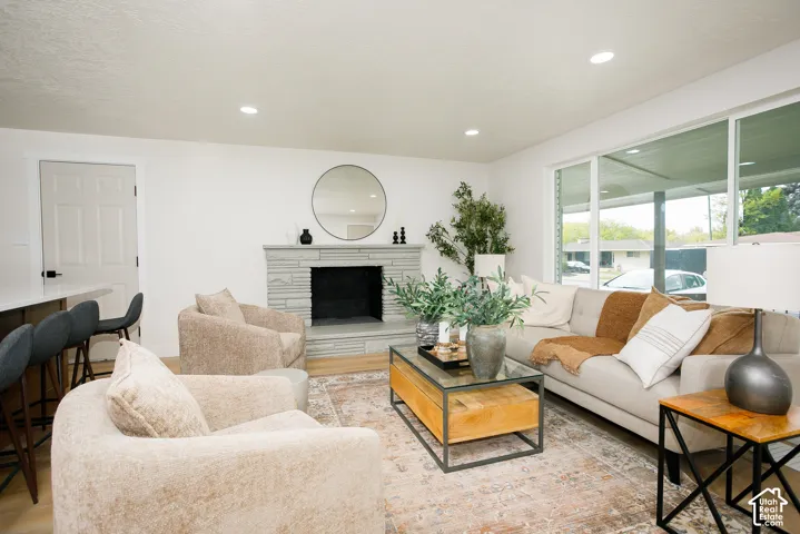 Stone masonry fireplace with a raised hearth, wood-finish flooring, recessed lighting, and large windows