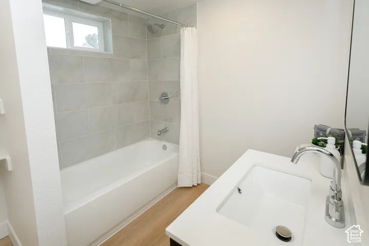 Bathroom featuring a porcelain tub with large-format tile surround, chrome shower hardware, vanity with a white composite countertop, integrated rectangular sink, and polished chrome faucet