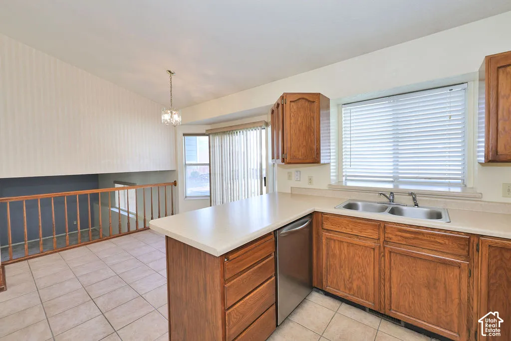 Kitchen featuring wood cabinetry, a stainless steel dishwasher, double-basin sink, tile flooring, and a vaulted ceiling with an overhead light fixture
