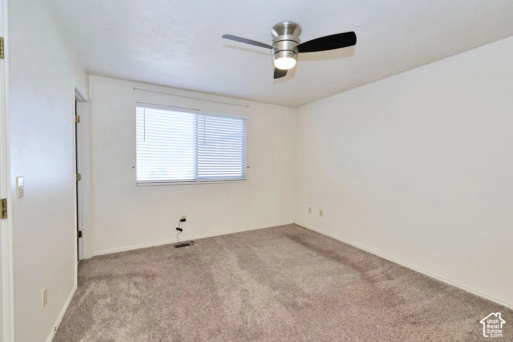 Room featuring neutral-toned carpeting, a horizontal sliding window with fitted blinds, and a ceiling-mounted light fixture with a fan