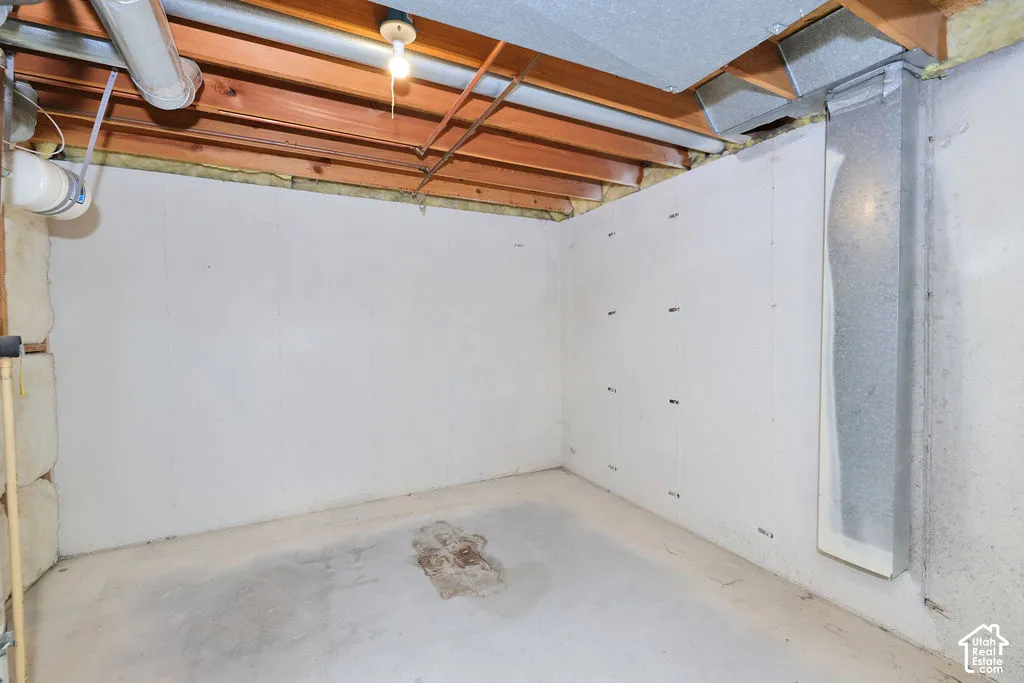 Unfinished utility space featuring exposed wood joist ceiling, painted concrete wall panels, and concrete flooring