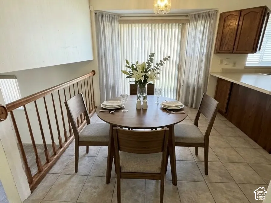 Tile flooring, vaulted ceilings, wooden spindle stair railing, pendant lighting, and a sliding glass door