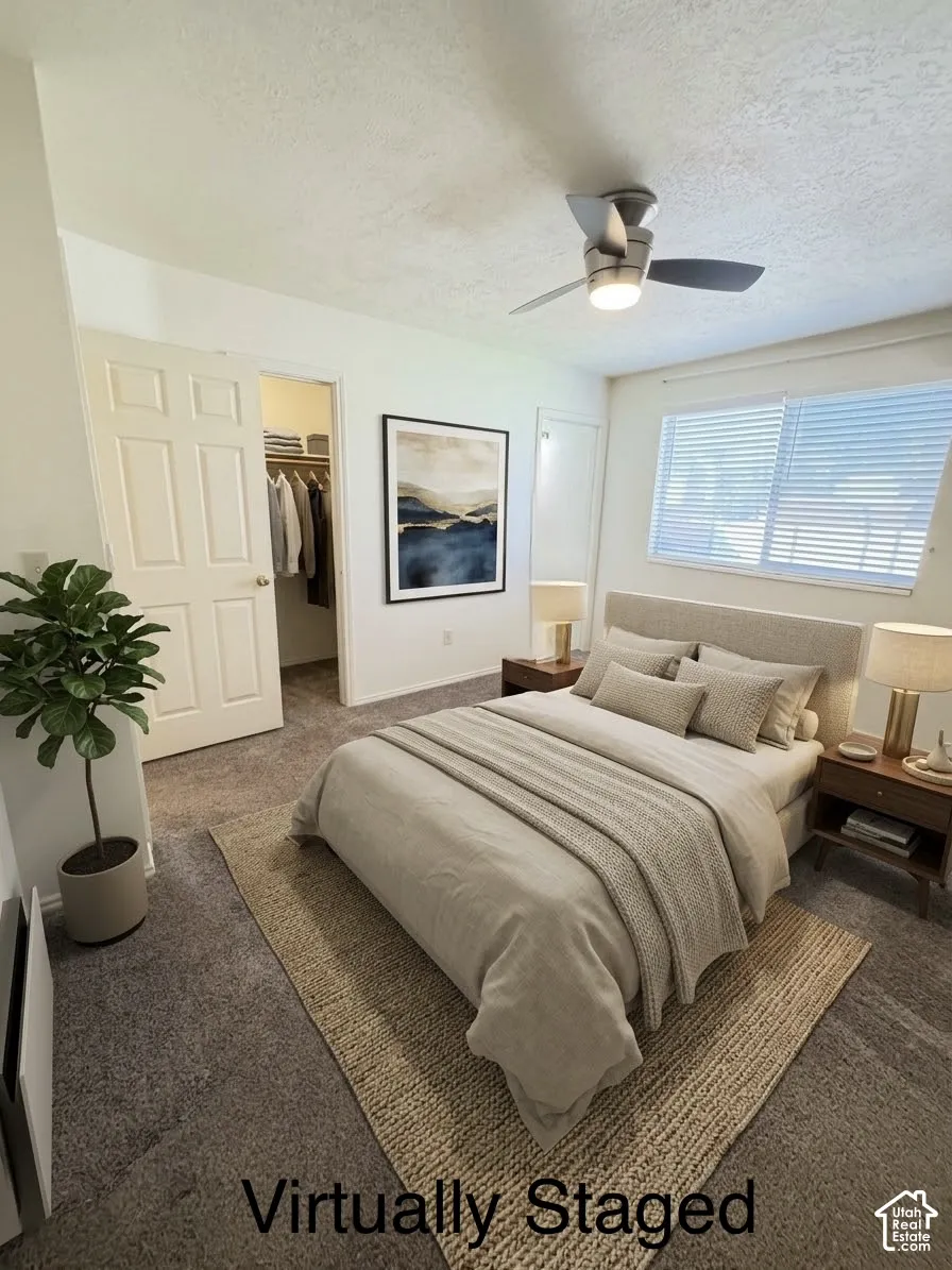 Bedroom featuring wall-to-wall carpeting, a multi-blade ceiling fan with integrated lighting, a walk-in closet, and a horizontal window with blinds