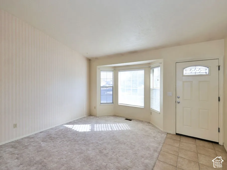 Vaulted ceilings, expansive bay window, tile-surfaced entryway, and paneled front door with decorative glass insert