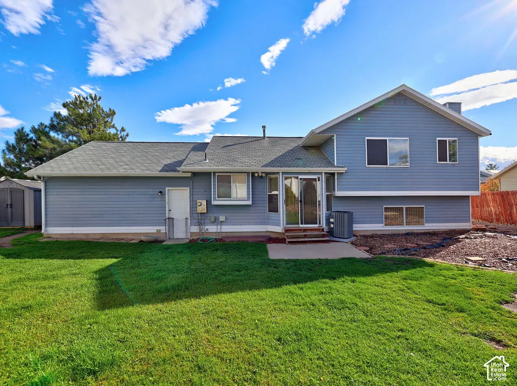 Blue lap siding exterior featuring a concrete patio, sliding glass door, shingle roof, and expansive lawn