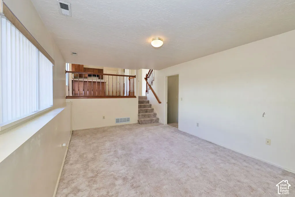 Interior space featuring wall-to-wall carpeting, vertical window blinds, and wood-finish handrails on the staircase and landing