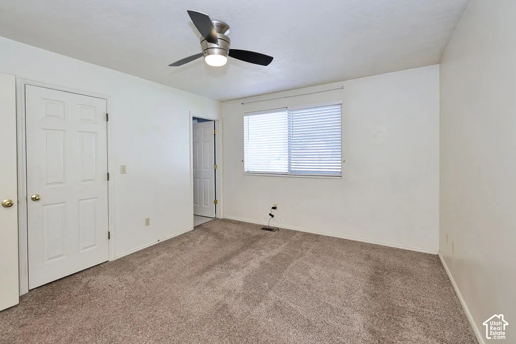 Neutral-toned carpeted flooring, multi-panel interior doors, and a brushed nickel ceiling fan with integrated lighting