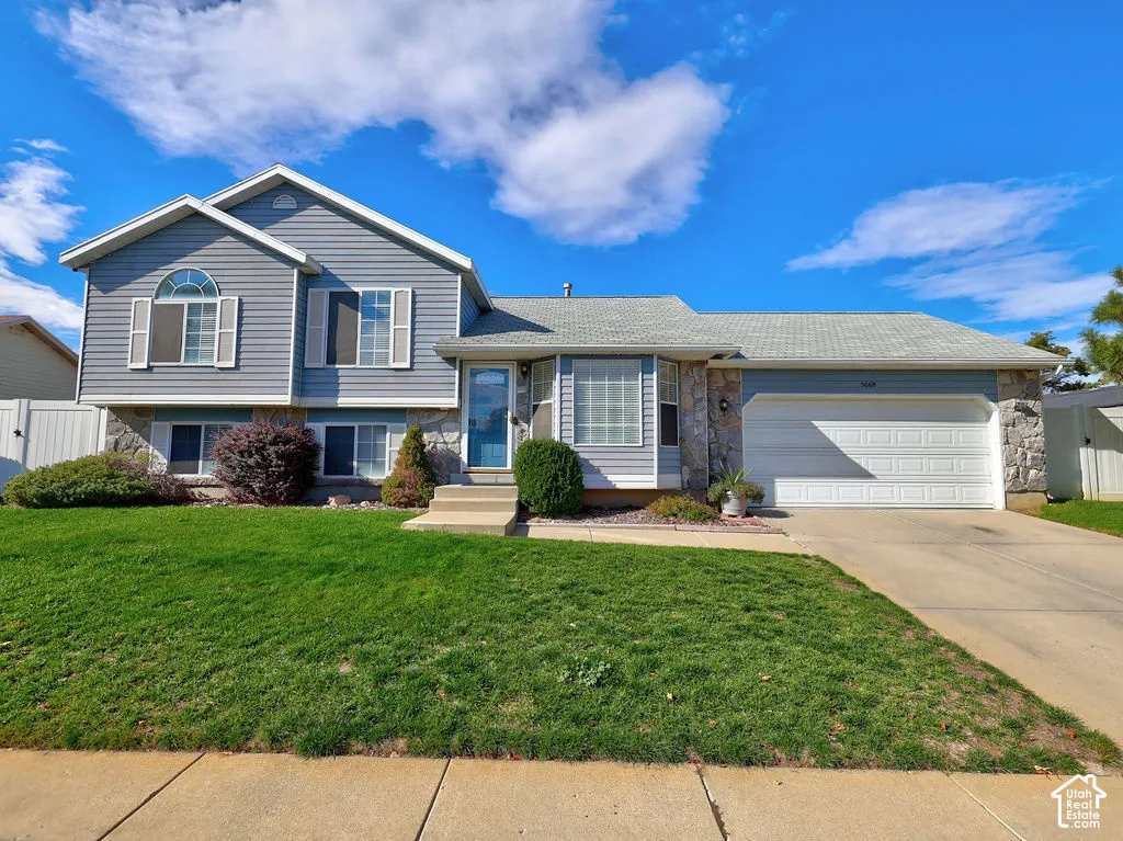 Multi-level exterior featuring horizontal lap siding, stone veneer accents, an attached two-car garage, and a multi-pane arched window