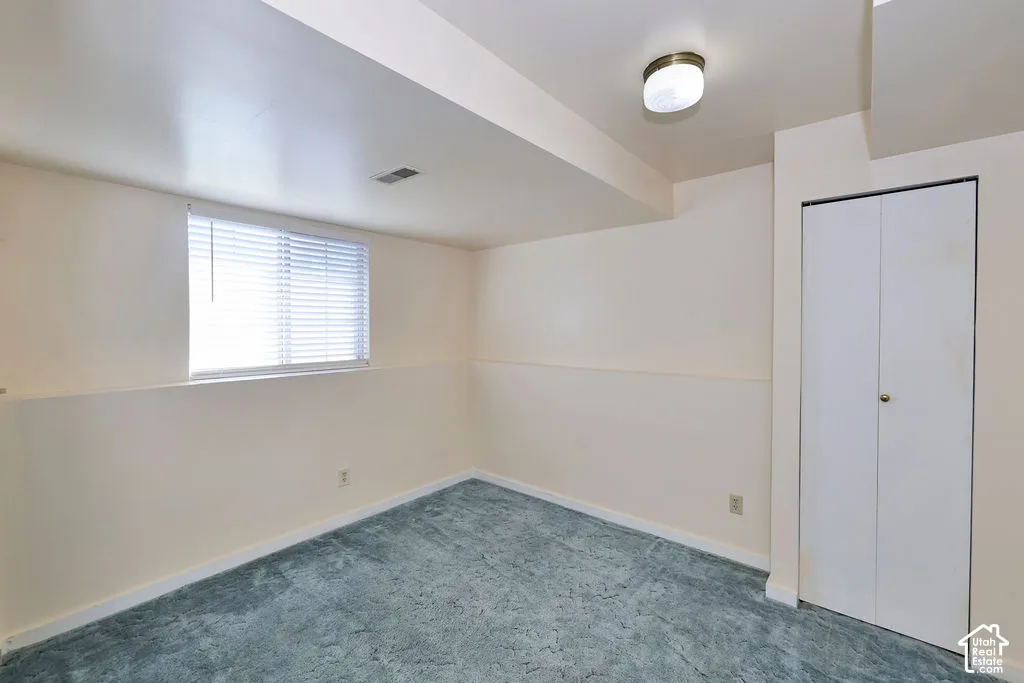 Room featuring wall-to-wall carpeting, a dual-panel closet, a single window with horizontal blinds, and a flush-mount ceiling light fixture