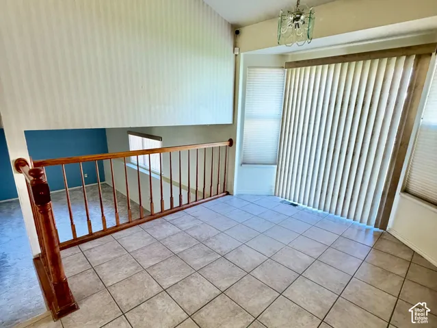 Vaulted ceiling, ceramic tile flooring, wood railing, and pendant lighting