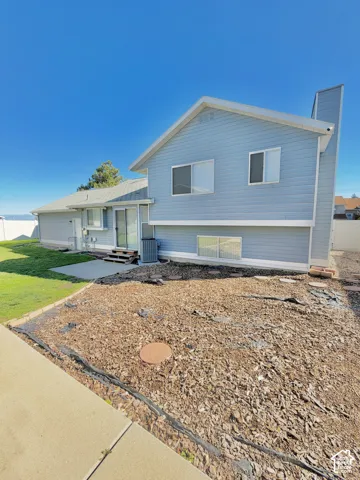 Two-story residence with horizontal siding, sliding glass rear entry, concrete patio, and fenced backyard