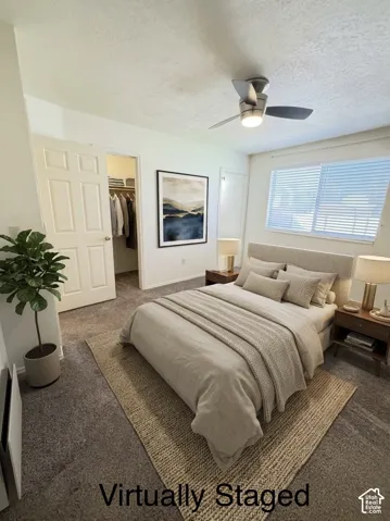 Bedroom featuring wall-to-wall carpeting, a multi-blade ceiling fan with integrated lighting, a walk-in closet, and a horizontal window with blinds