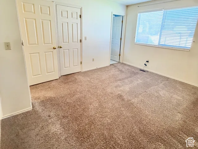 Neutral-toned wall-to-wall carpeting, ceiling fan with integrated lighting, and two sets of interior paneled doors