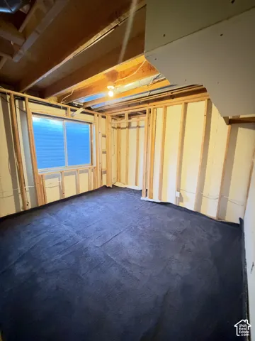 Unfinished interior space featuring exposed wood framing, an installed window, and a dark underlayment floor covering