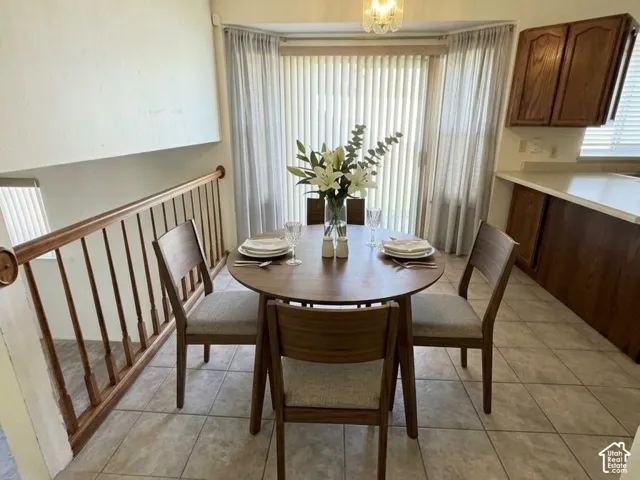 Tile flooring, vaulted ceilings, wooden spindle stair railing, pendant lighting, and a sliding glass door