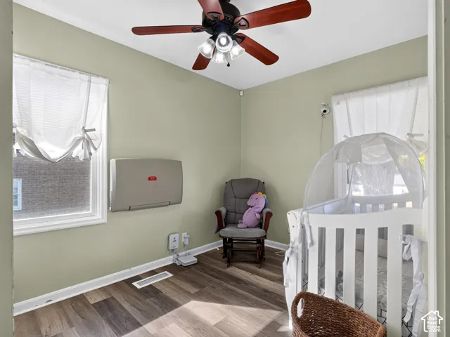 Wood-finish flooring, multi-blade ceiling fan with integrated lighting, and dual windows