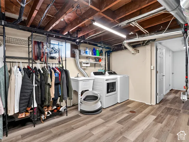 Laundry area featuring wood-finish flooring, a utility sink, and wall-mounted shelving