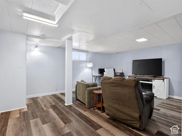 Finished interior space featuring light-toned paneled walls, wood-finish flooring, a drop ceiling with recessed lighting, and a horizontal sliding window