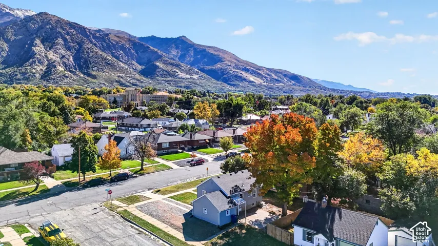 Aerial perspective featuring a mountain backdrop, mature trees, and established neighborhood landscaping