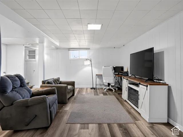 Finished interior space featuring wood-finish flooring, white paneling, a recessed light fixture, and an egress window