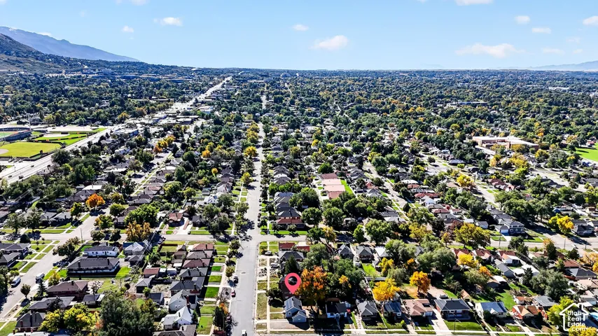 Aerial perspective of a residential neighborhood featuring mature trees and a mountain backdrop
