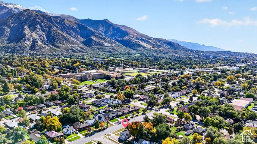 Aerial perspective of a residential lot set against a mountain backdrop featuring mature trees and established landscaping