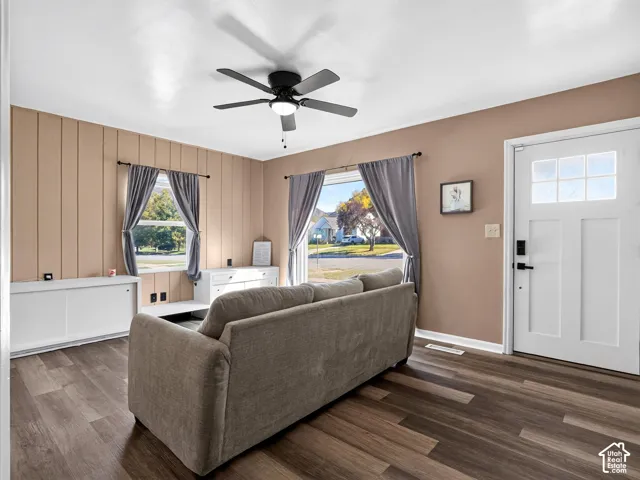 Vertical wood-paneled accent wall, wood-finish flooring, ceiling fan with integrated lighting, and multi-pane entry door