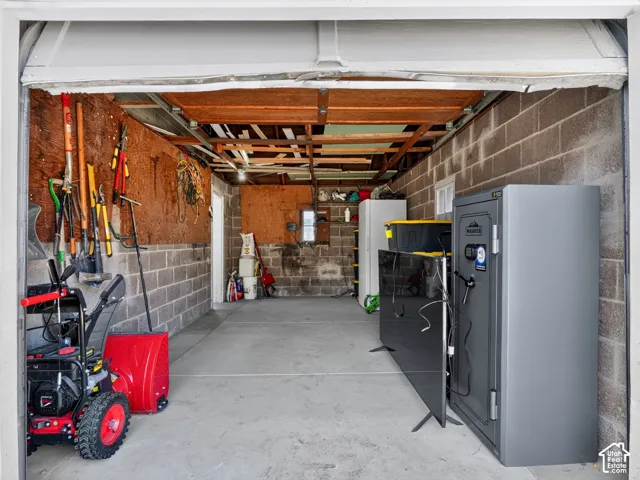 Single-car garage featuring concrete block walls, a concrete floor, and exposed ceiling joists