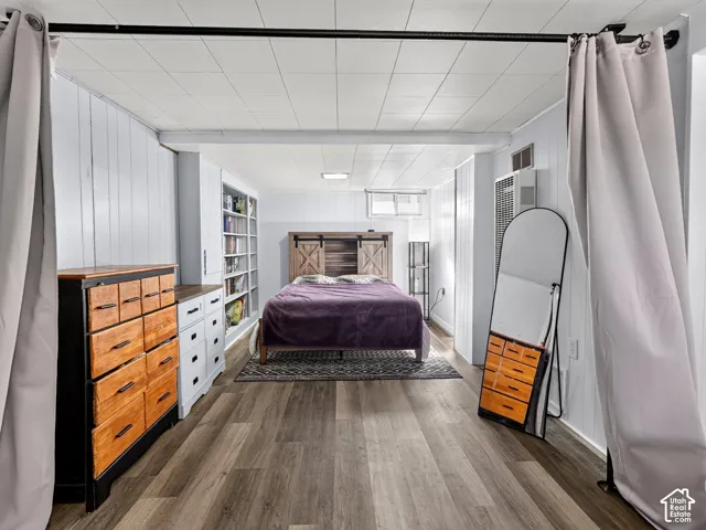 Interior space featuring panelled walls, wood-finish flooring, built-in floor-to-ceiling shelving, and a ceiling-mounted curtain rod