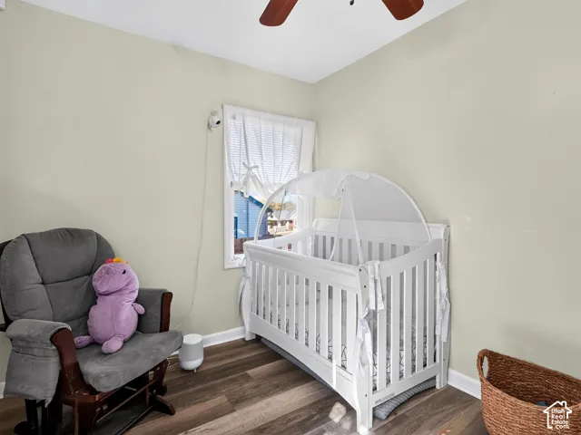 Room featuring wood-finish flooring, a single window with white trim, and a ceiling-mounted fan