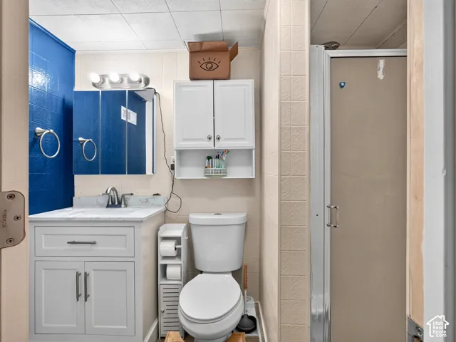Bathroom featuring a white vanity cabinet with a stone-finish countertop, tri-fold medicine cabinet, three-bulb vanity light, and a built-in wall cabinet