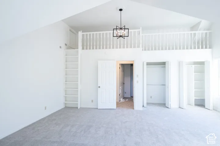 Vaulted ceiling with an exposed loft area, built-in ladder, perimeter railing, and a geometric pendant light fixture, complemented by dual built-in closets