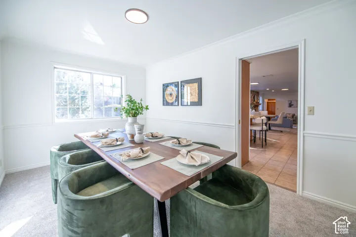 Dining area featuring wainscoting, neutral carpeting, and a multi-pane window