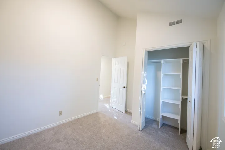 Room featuring vaulted ceilings, neutral-toned carpeting, and a closet with built-in shelving
