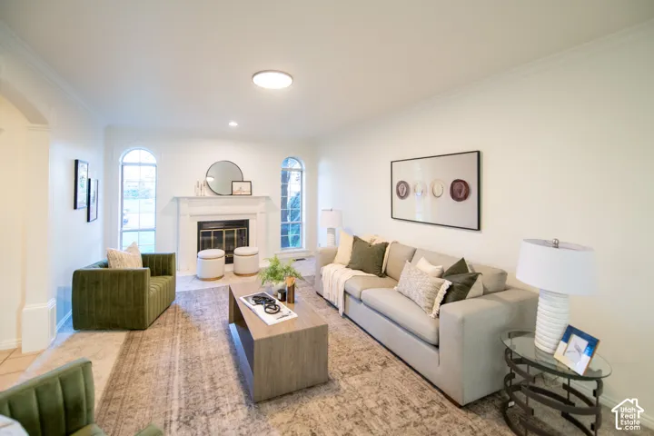 Living area featuring a fireplace with a white mantel, dual arched windows, crown molding, and recessed lighting