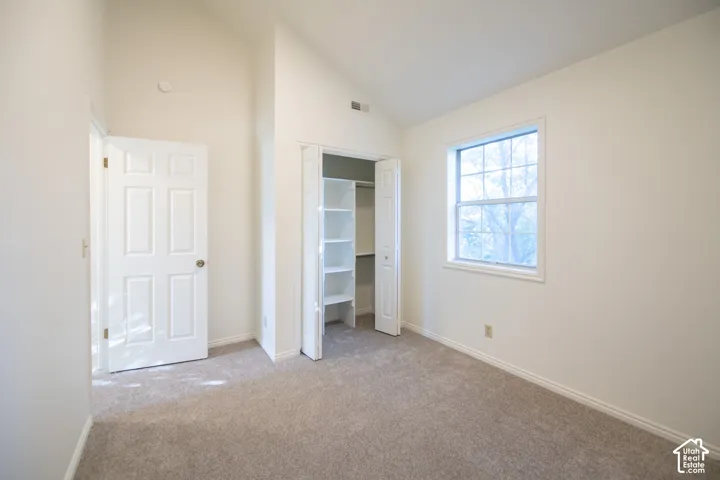 Vaulted ceiling, carpeting, built-in closet shelving, and a double-pane window
