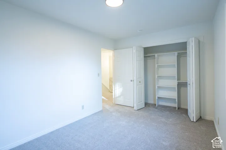 Neutral-toned carpeting, white walls, and a built-in closet with integrated shelving and dual bi-fold doors