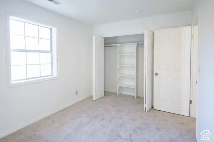 Room featuring carpeted flooring, a multi-pane window, and a closet with built-in shelving and folding doors