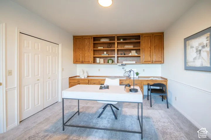 Built-in oak cabinetry featuring overhead shelving and integrated desk workspace, accompanied by double-door closet storage and wainscoting