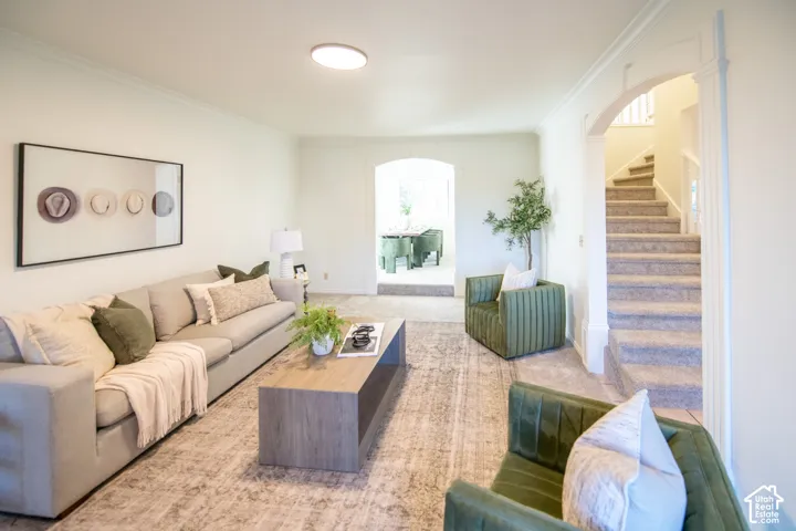 Neutral wall palette with rounded architectural archways, crown molding, and carpeted stairs