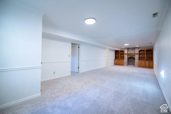 Expansive room featuring wall-to-wall carpeting, chair rail molding, a stone-surround fireplace, and built-in wood cabinetry