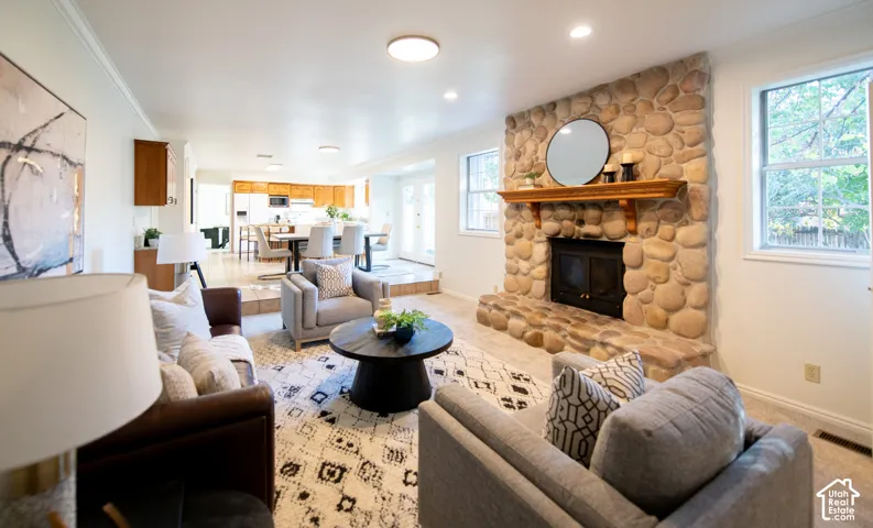 Floor-to-ceiling river rock fireplace with a built-in stone hearth and wooden mantel, recessed ceiling lighting, and crown molding