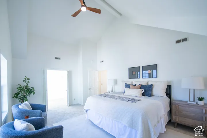 High vaulted ceiling with a modern ceiling fan and neutral wall-to-wall carpeting