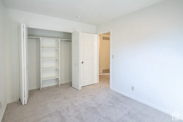 Neutral-toned carpeted flooring, bi-fold closet doors, and built-in shelving