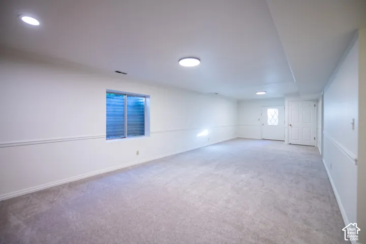 Open-concept interior featuring wall-to-wall carpeting, chair rail molding, recessed lighting, and an exterior door with a decorative glass insert