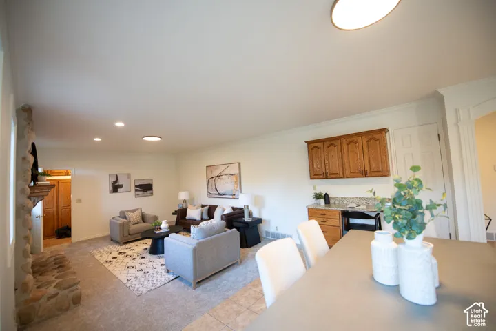 Floor-to-ceiling stone fireplace, cabinetry with wood-finish doors, light-toned stone-surface countertop, recessed ceiling lighting, and neutral carpeting