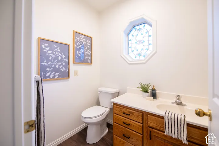 Octagonal leaded glass window, wood-finish cabinetry, integrated countertop with molded sink, and wood-finish flooring